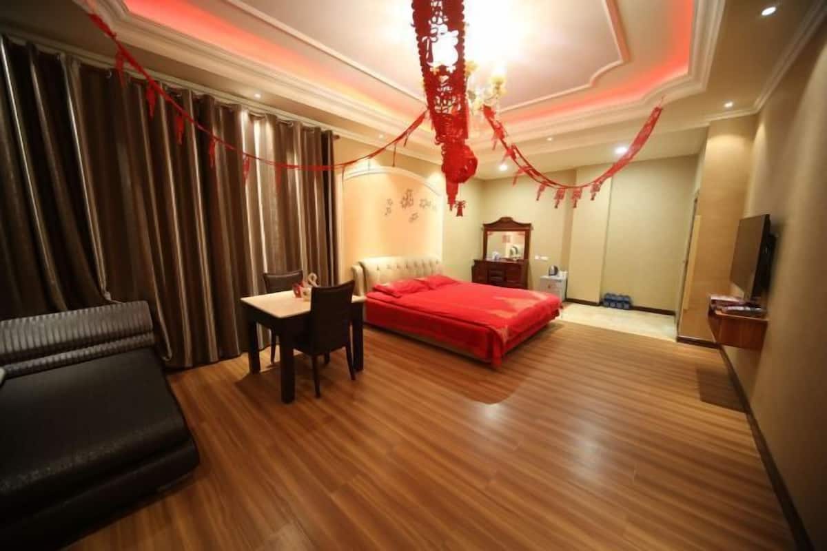 Una habitación de hotel con una cama, un escritorio, una silla, un televisor y cortinas.