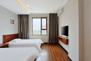 Une chambre d’hôtel avec deux lits, une télévision, une fenêtre avec des rideaux et une vue sur la ville.