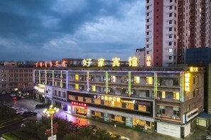 Un hôtel à plusieurs étages, doté d’une enseigne lumineuse, d’un parking et bordé d’immeubles de grande hauteur.