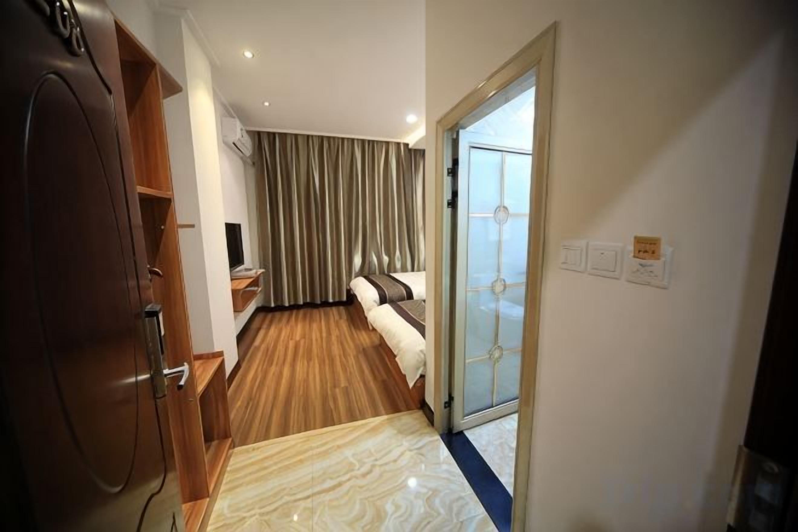 Een hotelkamer met een bed, een televisie, een houten garderobe en een glazen schuifdeur naar een balkon.