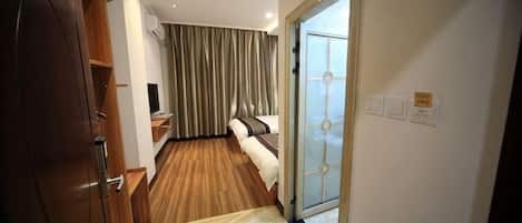 A hotel room with a bed, a TV, a wooden wardrobe, and a sliding glass door leading to a balcony.