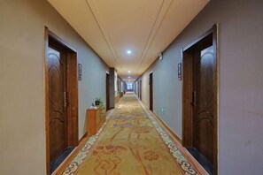 Un couloir d’hôtel avec des revêtements de sol en moquette, des portes en bois et un long couloir.