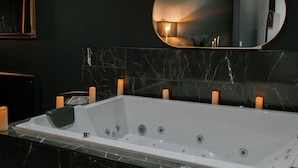 A bathroom with a large bathtub, a mirror, and candles on the wall. - Romantic Night Getaway (Cherbourg-en-Cotentin)