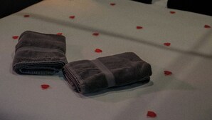 A neatly made bed with a white sheet and red rose petals scattered across it. - Romantic Night Getaway (Cherbourg-en-Cotentin)