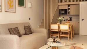Una sala de estar con un sofá, almohadones estampados, una mesa de centro y un comedor con sillas y una mesa.