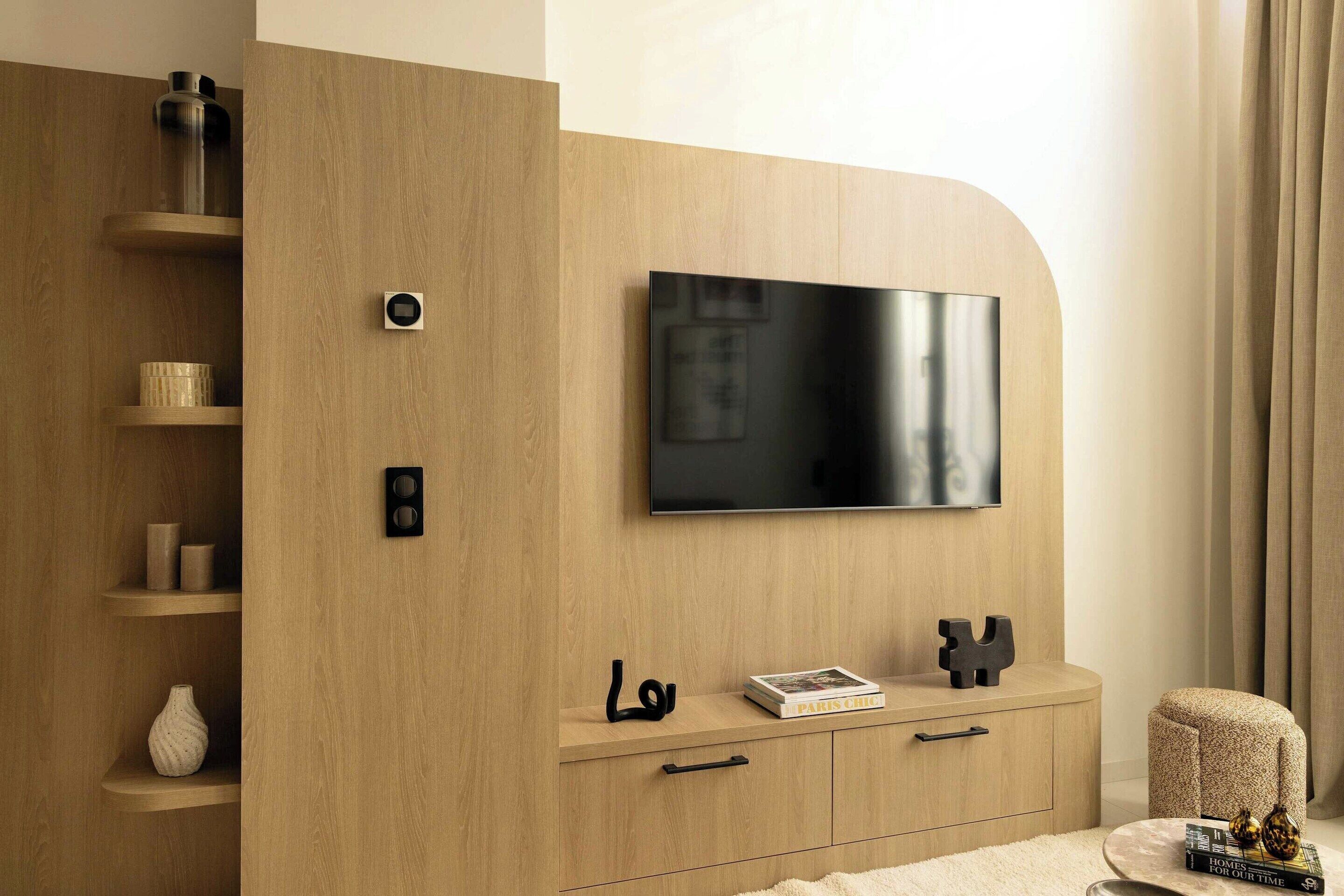 A modern living room with a wooden TV stand, a flat-screen TV, and a cozy seating area.
