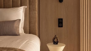 Un dormitorio moderno con una cama grande, una mesita de noche original y una lámpara en el techo.