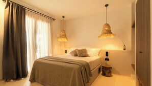 A bedroom with a bed, two bedside lamps, a bedside table, and a curtain.