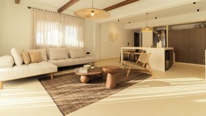 A modern living room with a sofa, coffee table, and a dining area.
