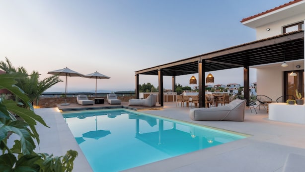 A rooftop pool area with lounge chairs, umbrellas, and a view of the cityscape.