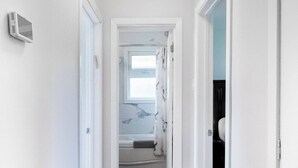 A hallway with wooden flooring, white walls, and a ceiling light fixture. - Beautiful Home In A Prime Location (Winnipeg)
