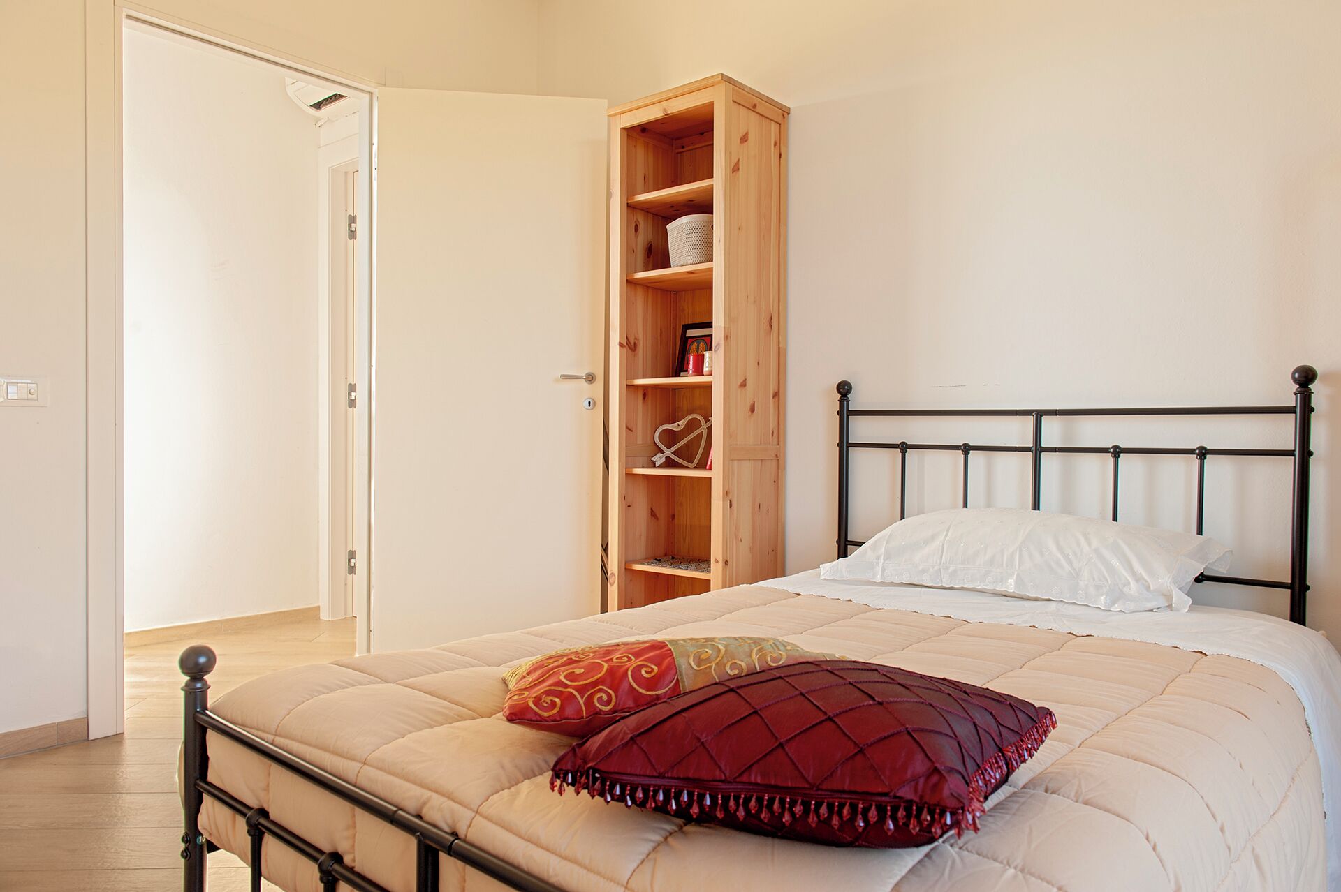 A bedroom with a bed, a wooden wardrobe, and a door.
