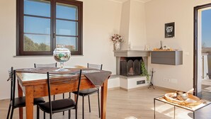 A dining area with a wooden table and chairs, a fireplace, and a window with a view of the outdoors. - La TOSCANELLA - Terricciola house -House with garden (Selvatelle)