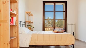 A bedroom with a bed, wooden bookshelves, a window with a view, and a radiator. - La TOSCANELLA - Terricciola house -House with garden (Selvatelle)
