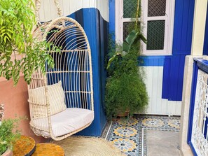A room with a hanging chair, a potted plant, and a patterned floor. - Riad 10 Mandarin (Marrakech)