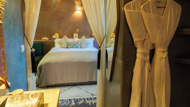 Quarto de hotel com cama, roupão pendurado na parede e espelho.