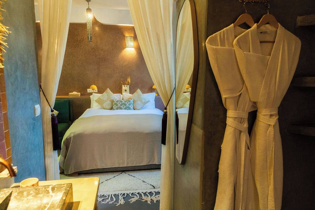 A hotel room with a bed, a robe hanging on the wall, and a mirror.