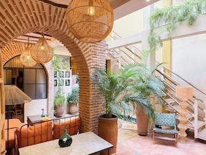 A spacious indoor area with a brick wall, a staircase, and various potted plants. - Riad 10 Mandarin (Marrakech)