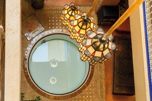 A circular skylight with a mosaic design, a hanging chandelier, and a patterned floor. - Riad 10 Mandarin (Marrakech)