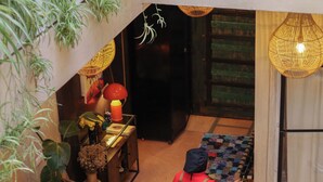 Um saguão de hotel com piso ladrilhado, balcão de recepção e uma pessoa caminhando.