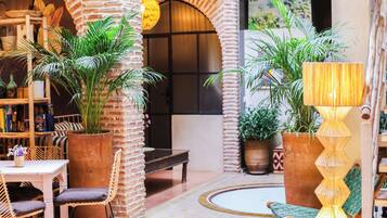 Un patio interior acogedor con paredes de ladrillo, muebles de madera y plantas en macetas.