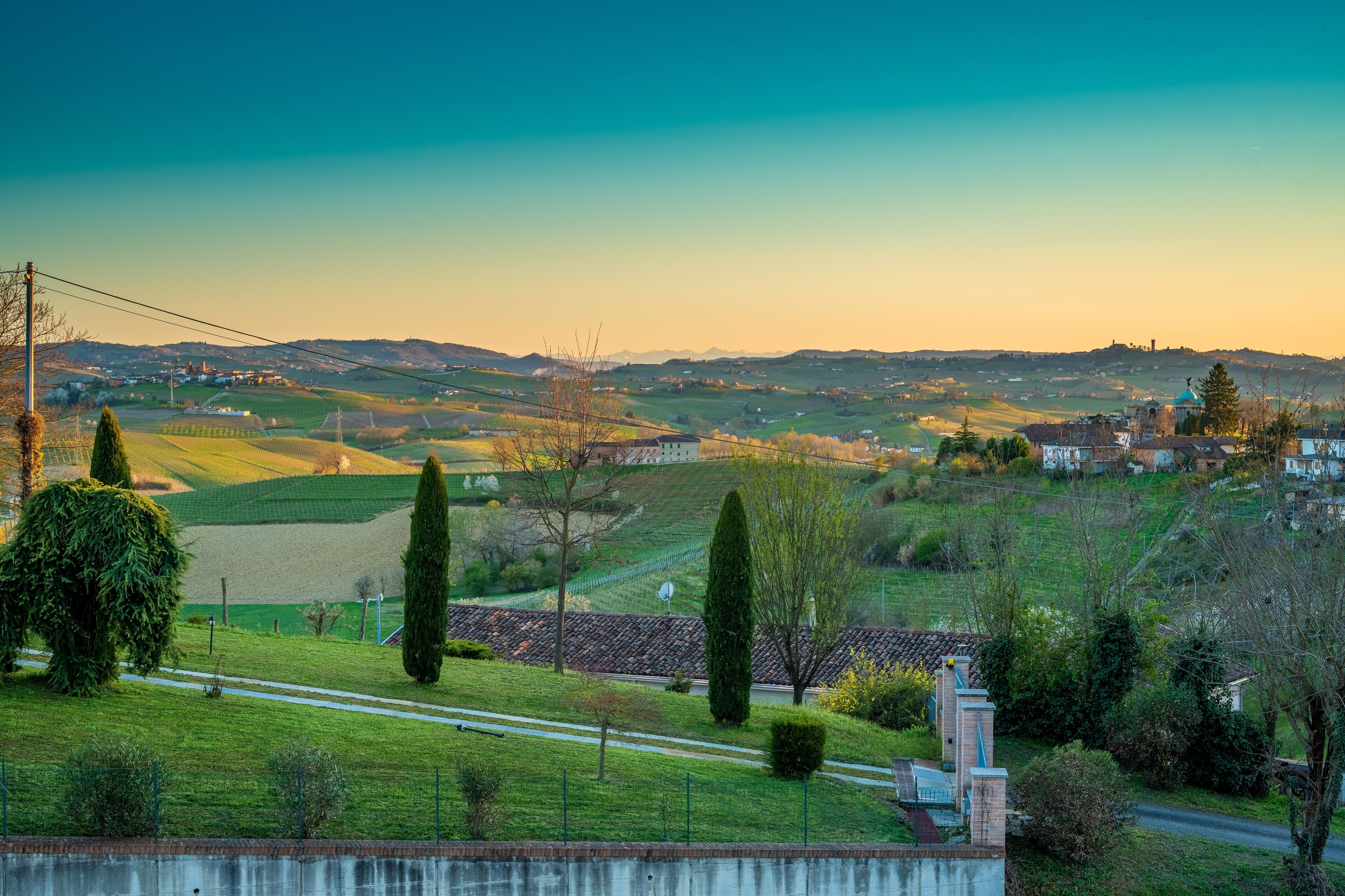 Un paysage rural avec des collines douces, une route et un petit bâtiment doté d’une tour.