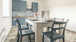 A modern kitchen with blue cabinets, a tiled backsplash, and a dining table set for four.