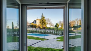 A view through a glass door of a swimming pool area with a house in the background.