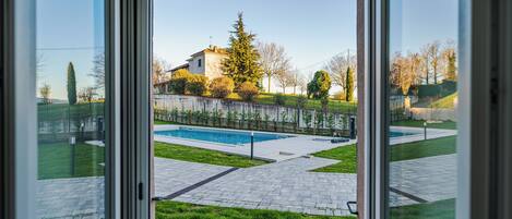A view through a glass door of a swimming pool area with a house in the background.