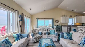 A spacious living room with a large window, a dining area, and a kitchen.