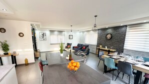 A modern living space with a dining area, a sofa set, and a kitchen counter.