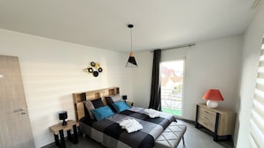 A modern bedroom with a bed, bedside tables, a lamp, and a view of the outside.