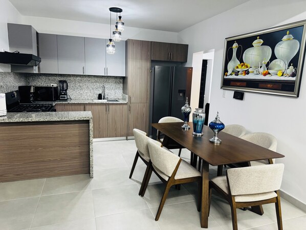 Cocina moderna con comedor, que presenta encimera de granito, electrodomésticos de acero inoxidable y una mesa con sillas.