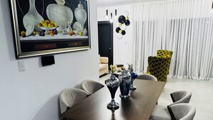 Un comedor con una mesa larga, seis sillas y un cuadro en la pared.