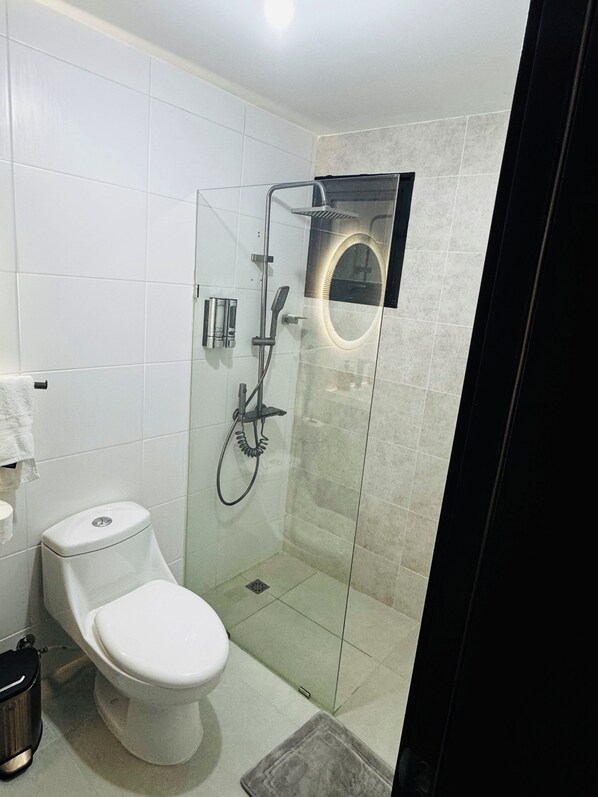 Un baño moderno con ducha acristalada, inodoro y lavamanos.