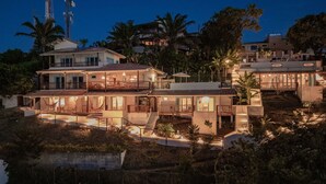 A multi-story house with a large balcony, outdoor seating, and a swimming pool.
