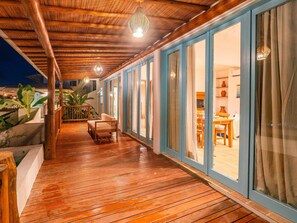 A wooden deck with a bench and a table, leading to a room with a view. - Vila Maya 4 - Stunning View in Itacaré (Itacaré)