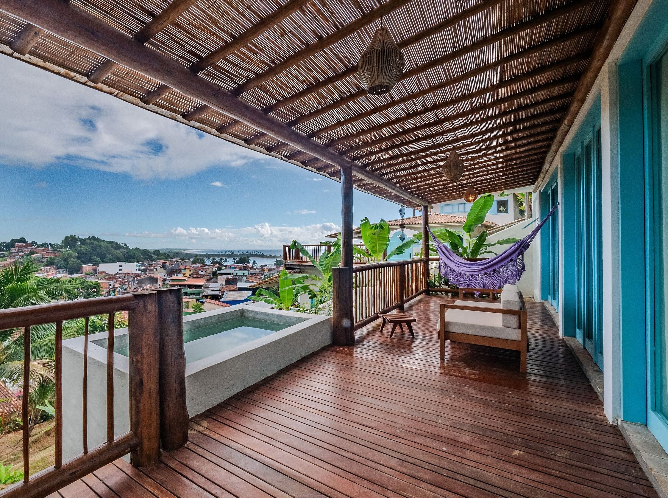 A wooden deck with a view of a cityscape, a hammock, and a small seating area.