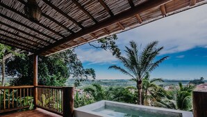 A wooden deck with a glass-enclosed hot tub overlooking a lush landscape.
