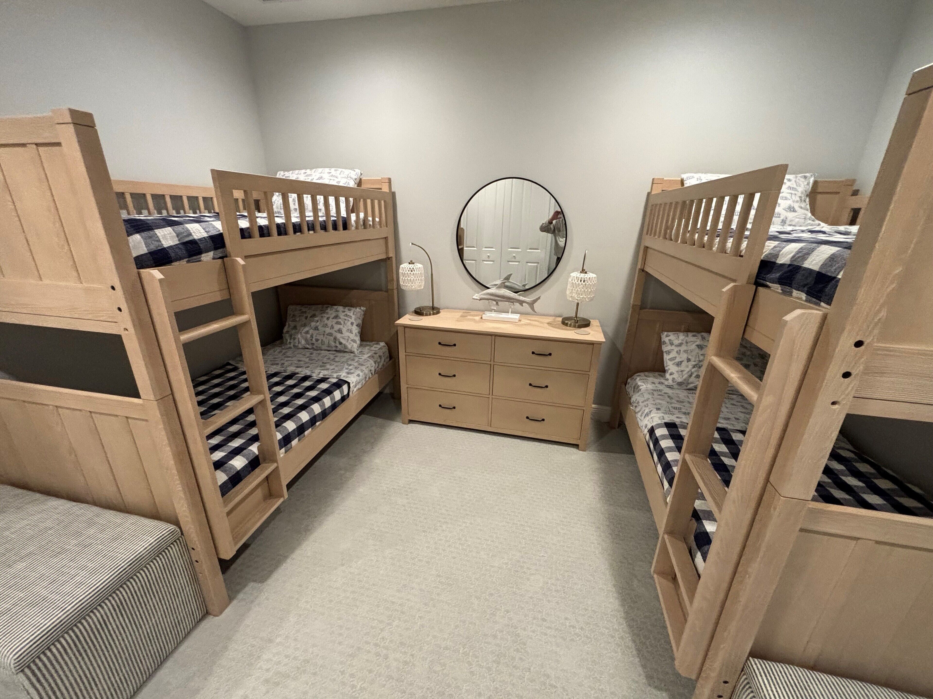 Een kamer met stapelbedden, een dressoir en een spiegel.