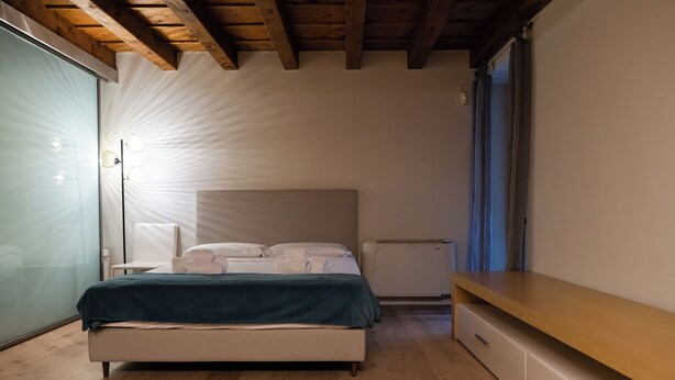 A bedroom with a bed, bedside table, and a built-in bench. - Residenza Balena (Verona)