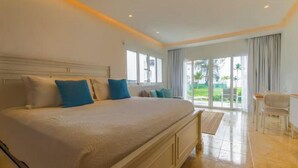 Un dormitorio amplio con una cama grande, un escritorio y vistas a un jardín a través de puertas corredizas de vidrio.