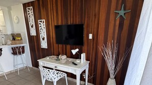 Un área de comedor con una mesa y sillas blancas, un televisor de pantalla plana montado en una pared de madera y una estrella decorativa.