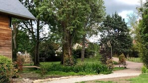 A wooden building with a gravel path leading to a grassy area. - Villa Nature (Pougny)