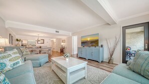 A spacious living room with a dining area, a television, and a view of the outdoors.