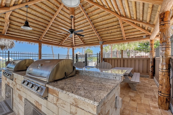 An outdoor barbecue area with a grill, a fan, and a table.