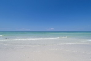 A beach with clear water and a clear sky.