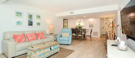 A living room with a sofa, armchairs, a coffee table, and a dining area with a table and chairs.