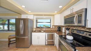 A modern kitchen with stainless steel appliances, a window with a view, and a tiled backsplash.