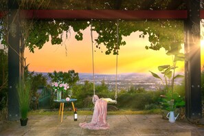 A swing set with a view of a sunset over a cityscape.